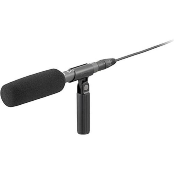 Ecm-673 | Spotx Close-up of a Black Handheld Microphone with a Foam Windscreen Mounted on a Small Stand for Recording or Broadcasting.